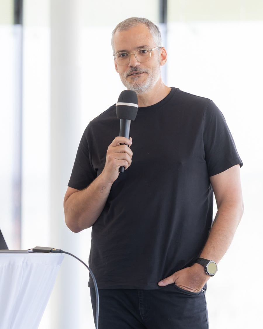 Gerald Aichholzer speaking at an AI talk, microphone in hand